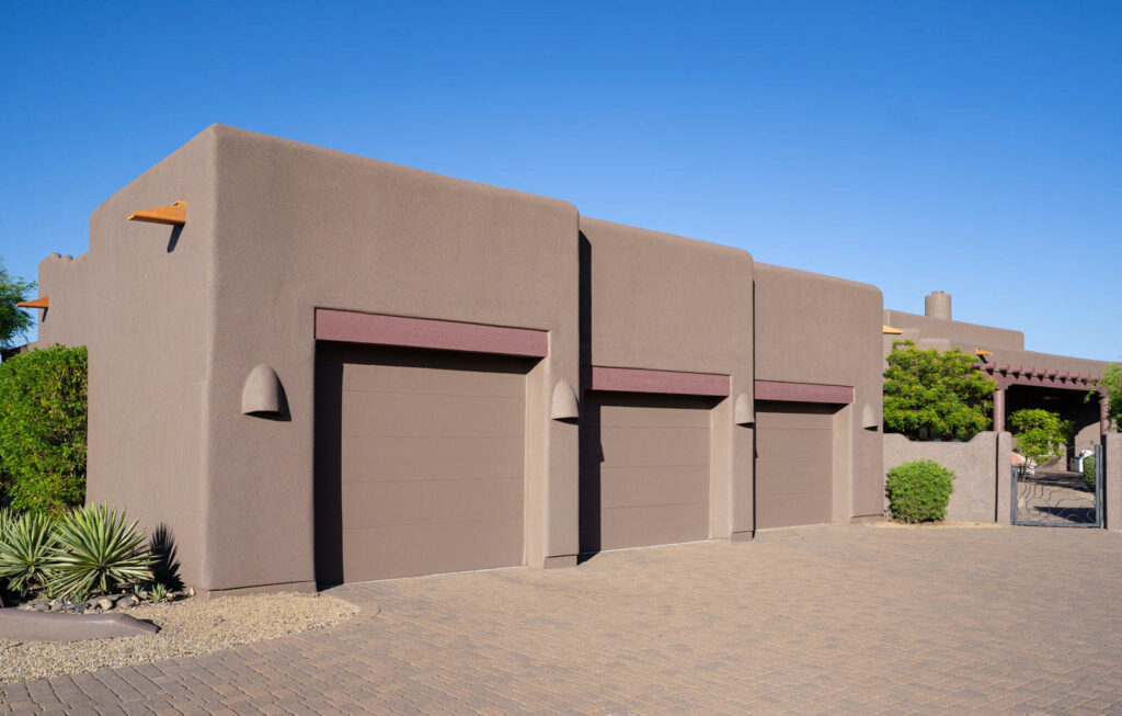 Three-car garage with newly painted doors, wood lintels and desert-tone stucco